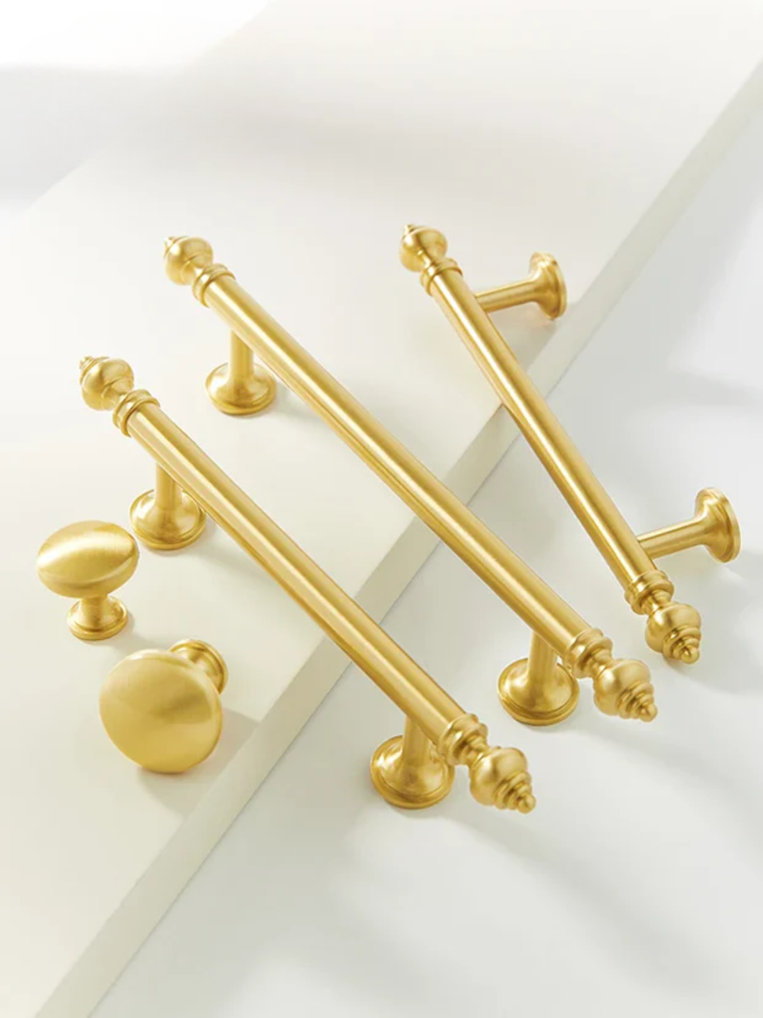 Gold cabinet handles and knobs on a white background
