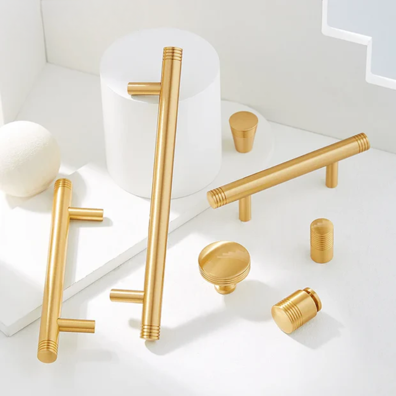Gold cabinet handles and knobs on a white surface