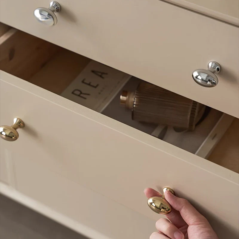 Hand opening a beige drawer with gold handles, revealing a brush inside.