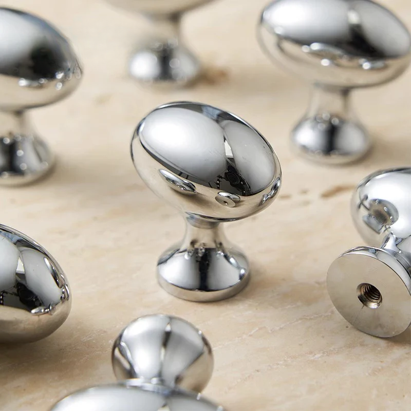Chrome cabinet knobs on a beige surface