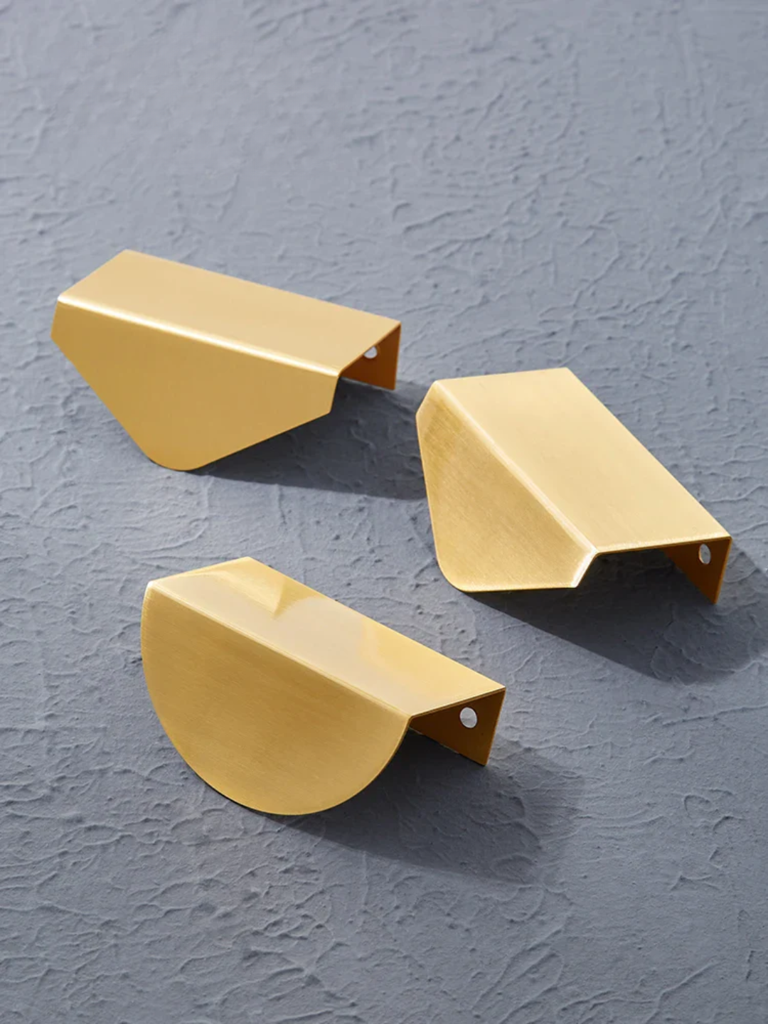 Three gold metal brackets on a gray textured background