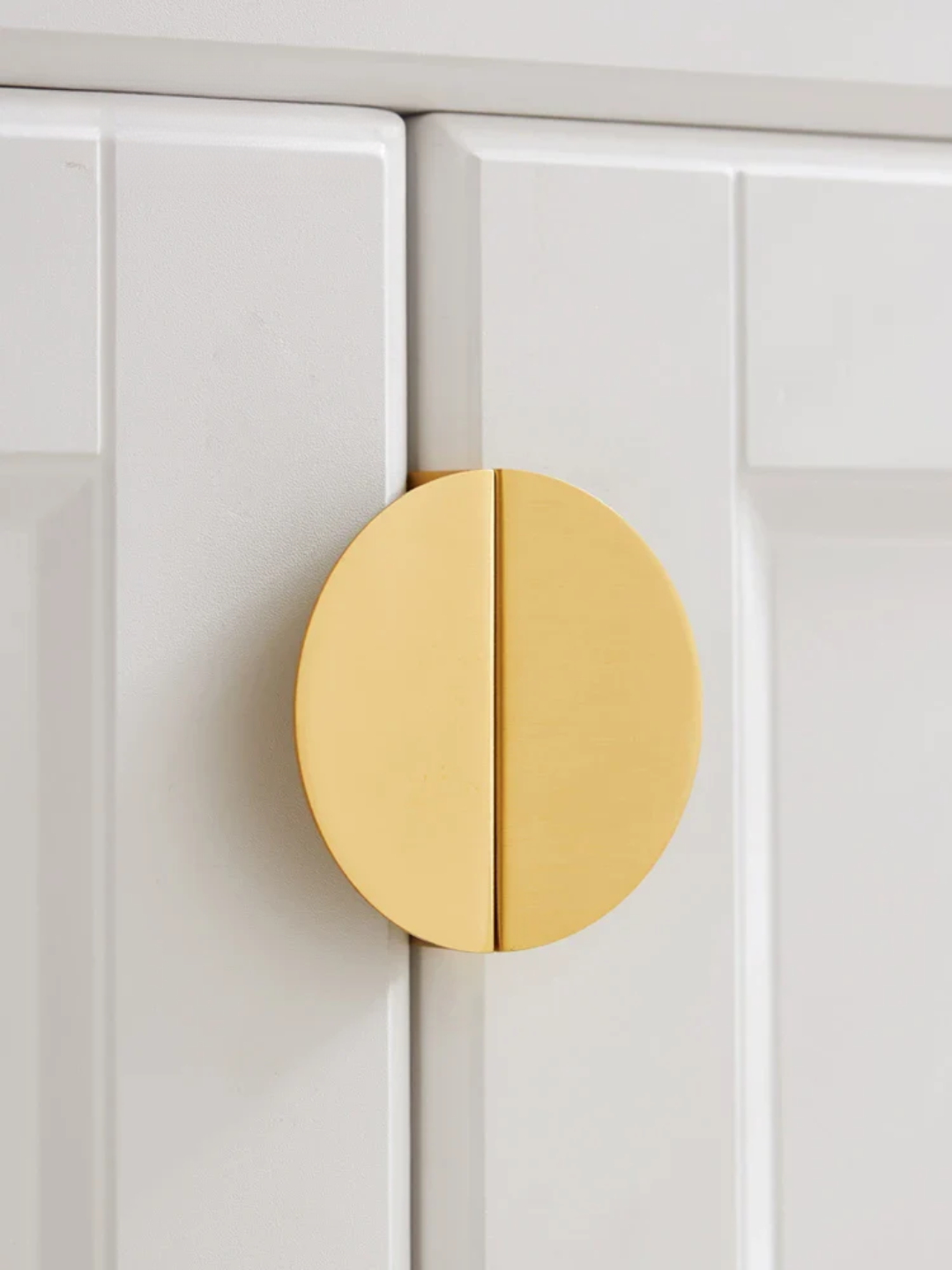 Gold cabinet knob on a white paneled door