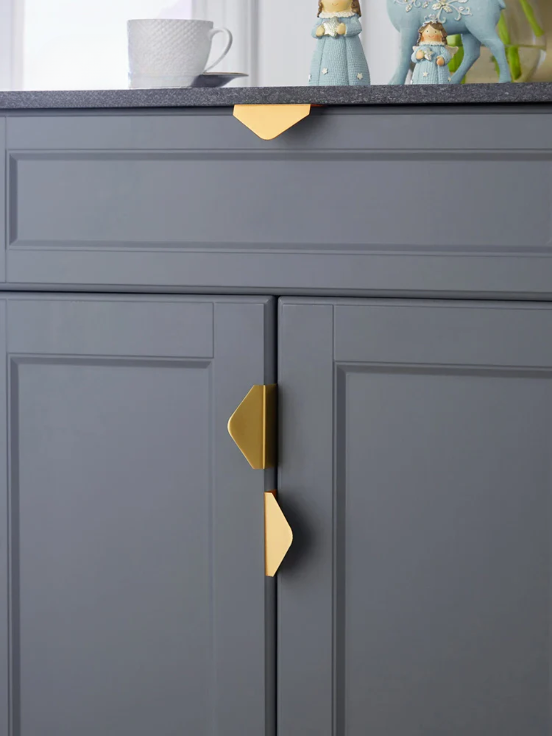 Gray cabinet with gold geometric handles in a kitchen setting