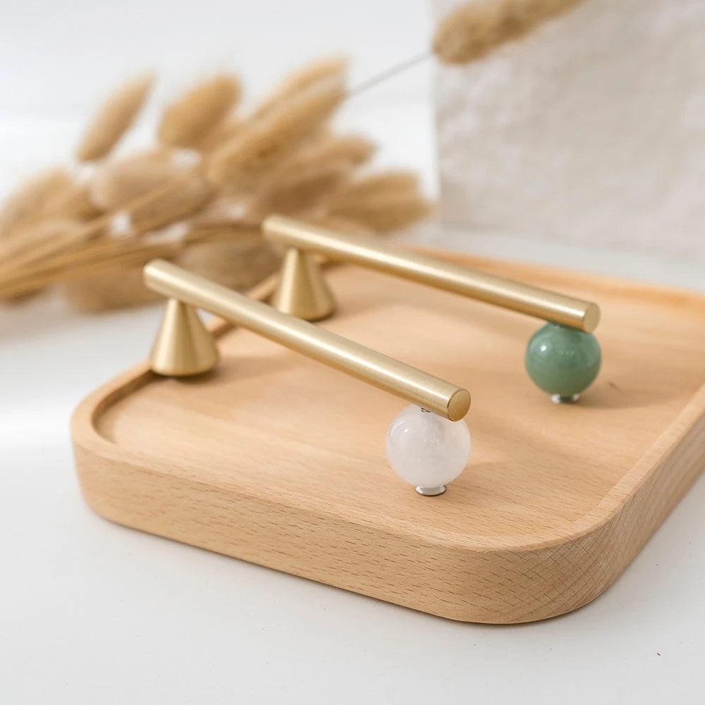 Green and white decorative cabinet hardware arranged on a wood tray