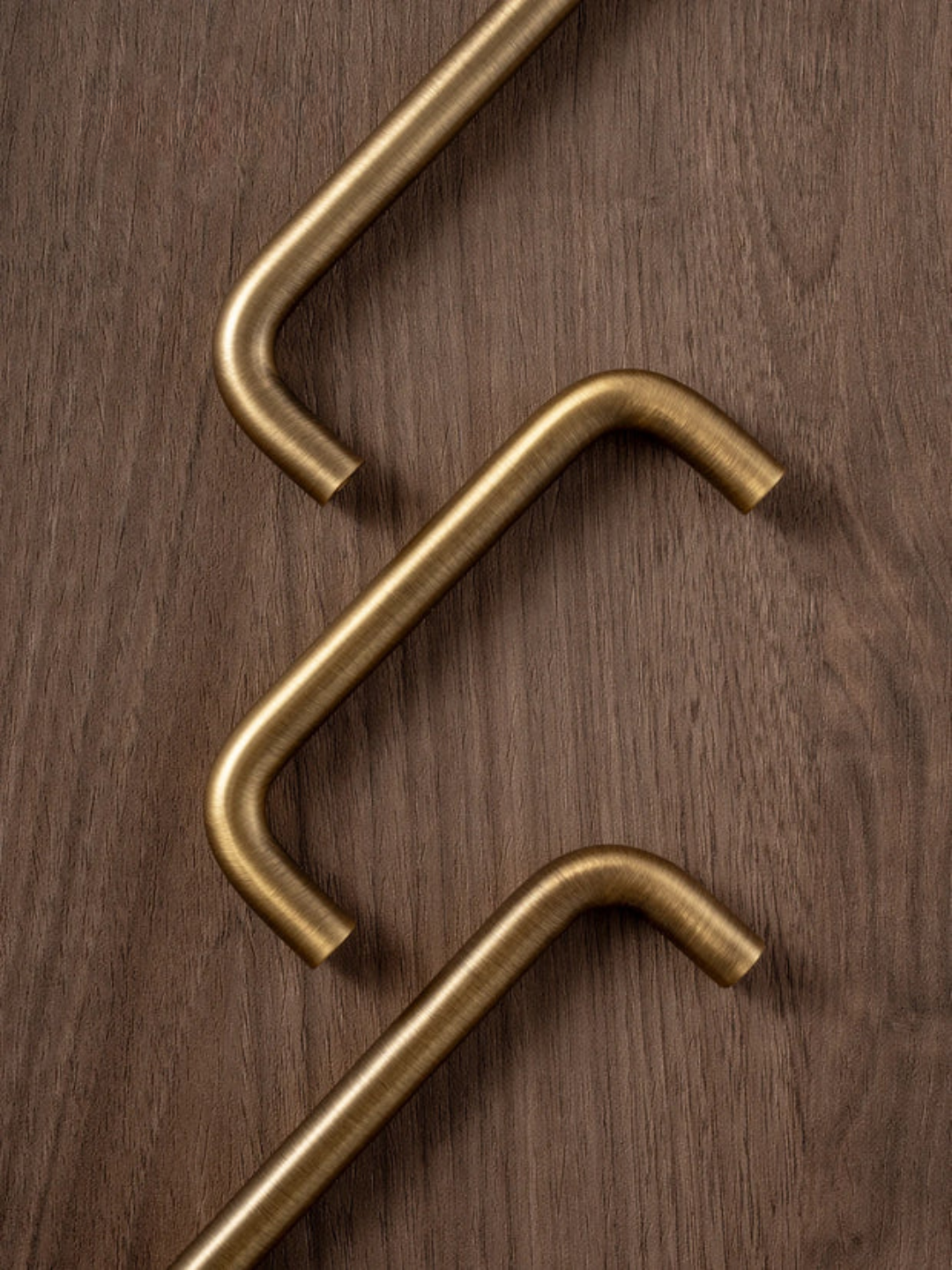 Three gold-colored handles on a wooden surface