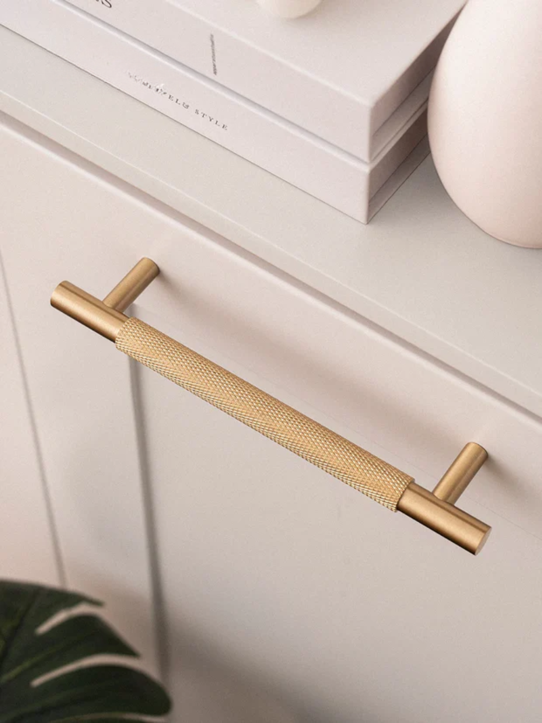 Brass cabinet handle on a white drawer with 'Santaya' branding.
