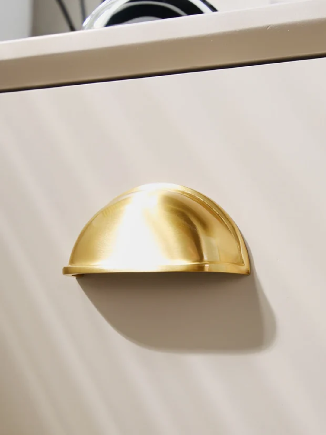 Gold cabinet handles and knobs on a light gray background