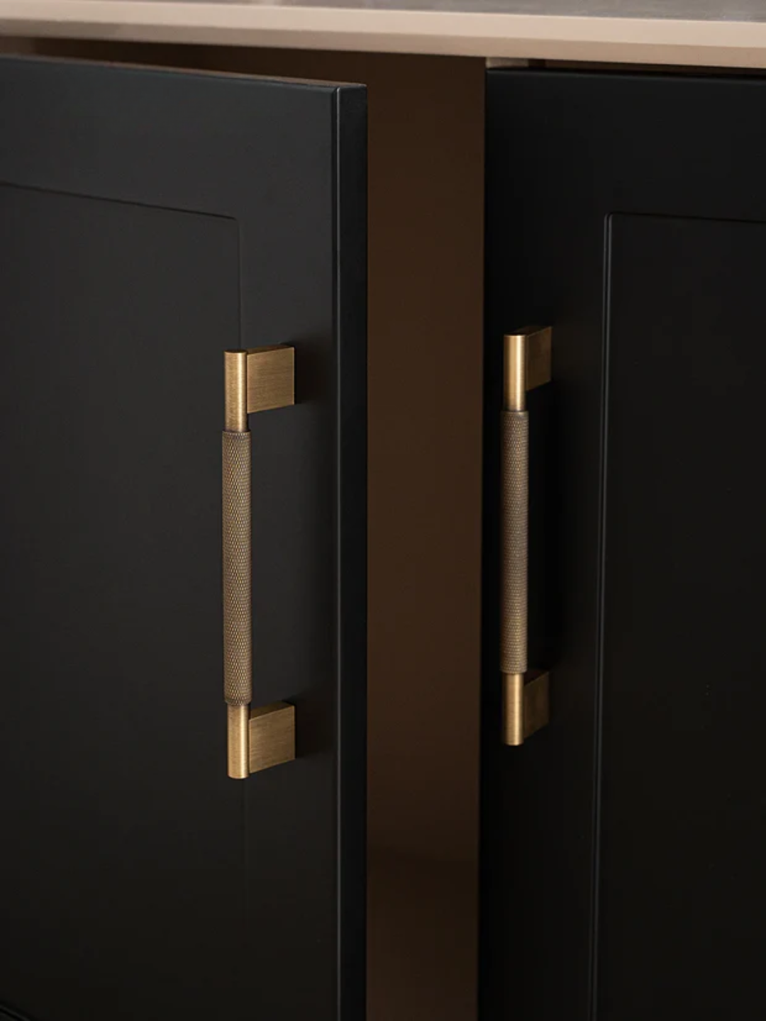 Black cabinet doors with gold handles on a kitchen counter.