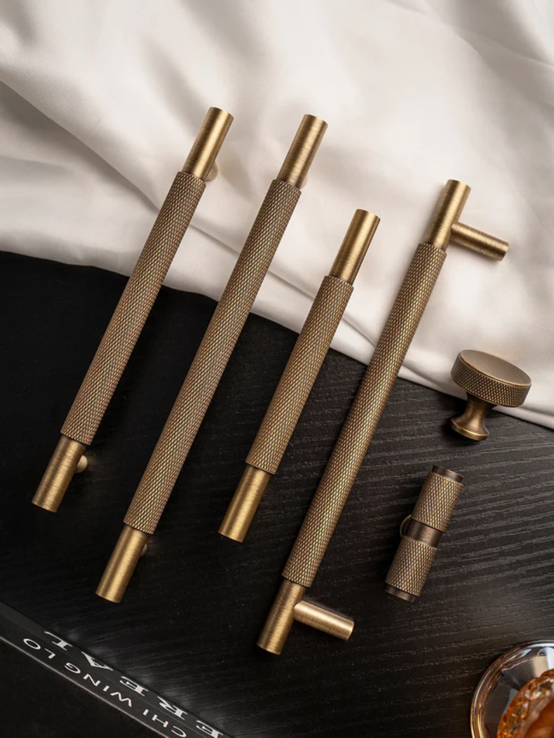 Set of gold metal handles on a textured surface with a white fabric background