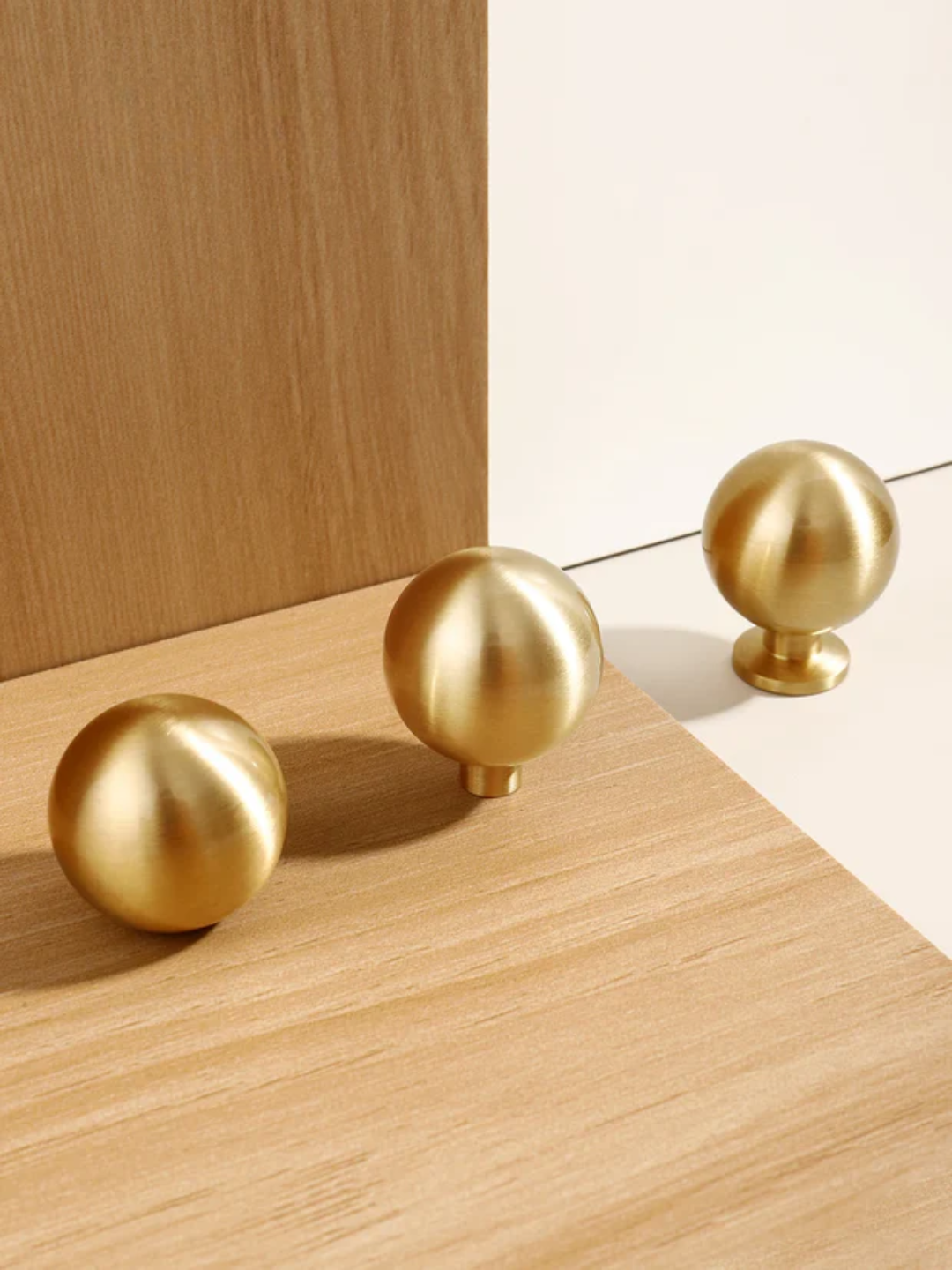 Three gold spherical objects on a wooden surface with a neutral background