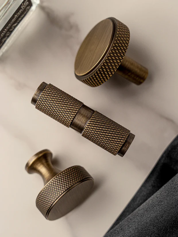 Three bronze cabinet knobs on a light background