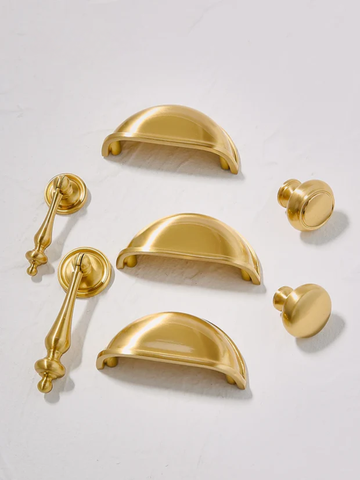 Gold cabinet handles and knobs on a light gray background