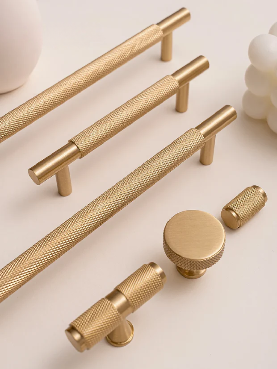 Collection of gold cabinet handles and knobs on a light background