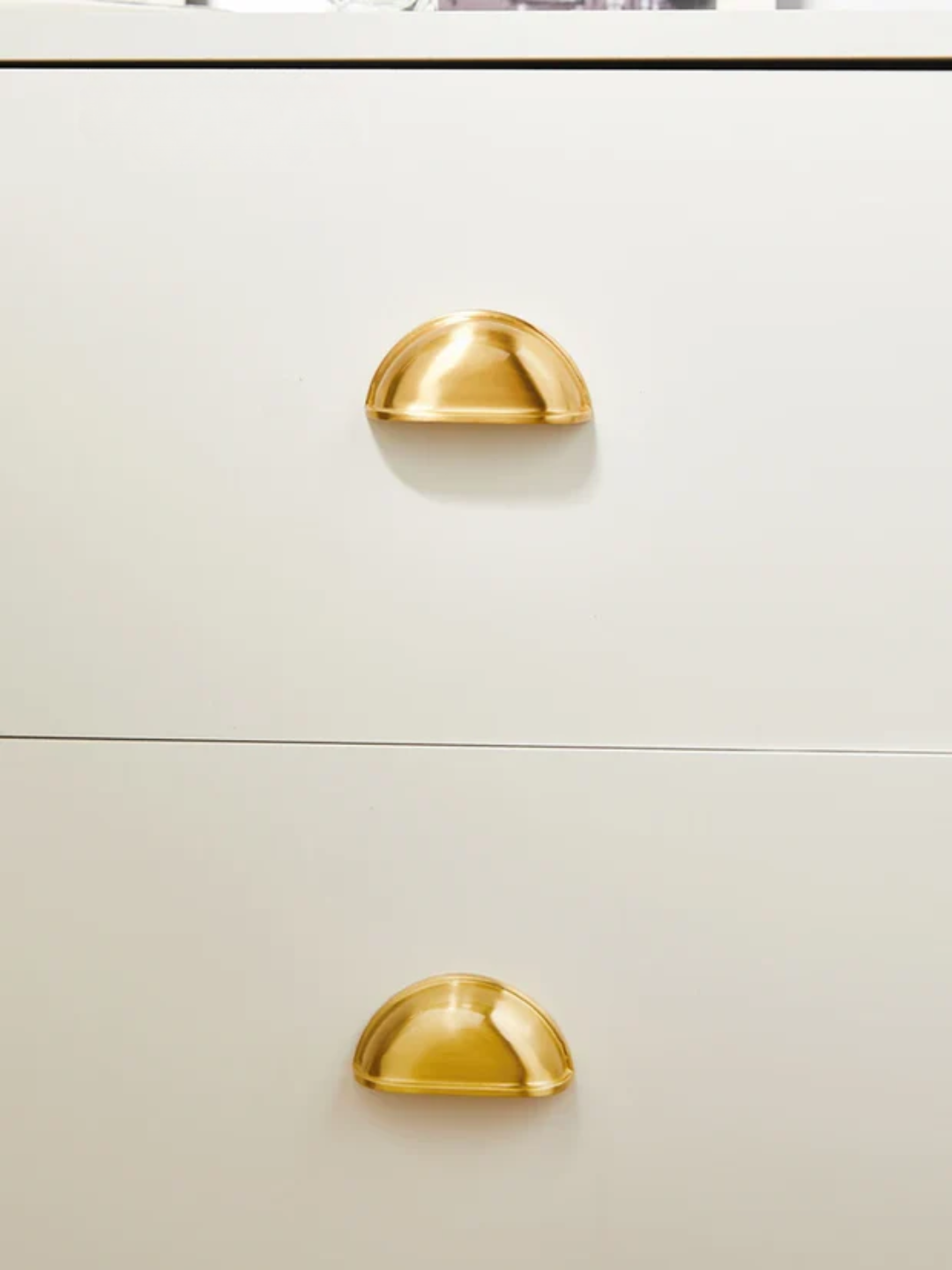 Close-up of a white cabinet with gold handles