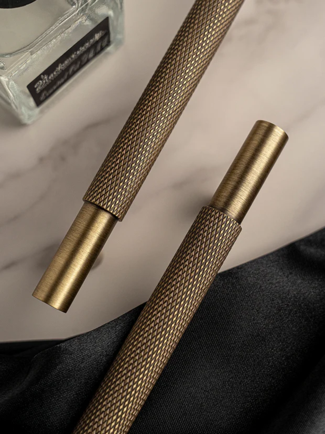 Two brass tools on a marble surface with a black fabric background