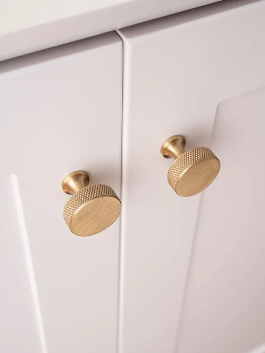 Close-up of white cabinet doors with gold knobs