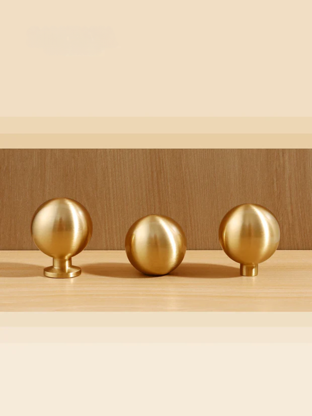 Three gold spherical objects on a wooden surface with a neutral background