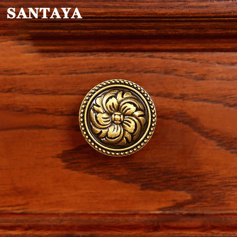 Decorative brass knob on a wooden surface with 'SANTAYA' branding.