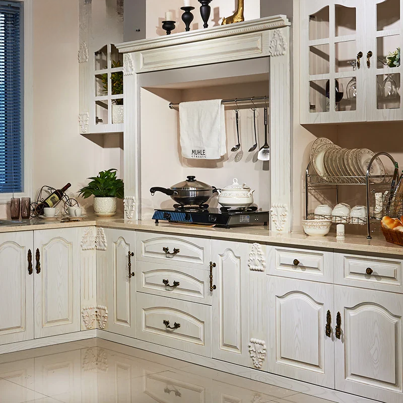Modern kitchen with white cabinets, stovetop, and various kitchen items.