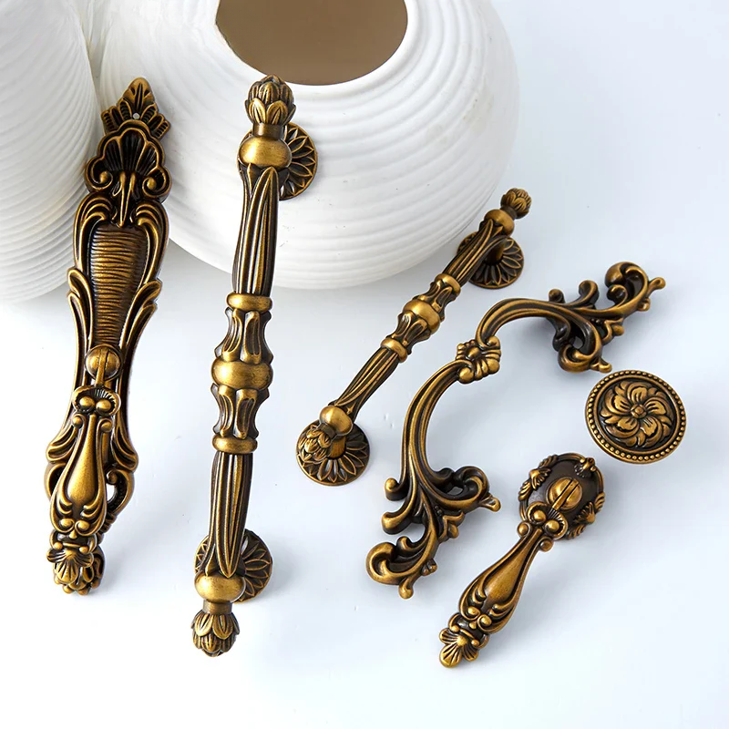 Collection of ornate brass cabinet handles on a white background