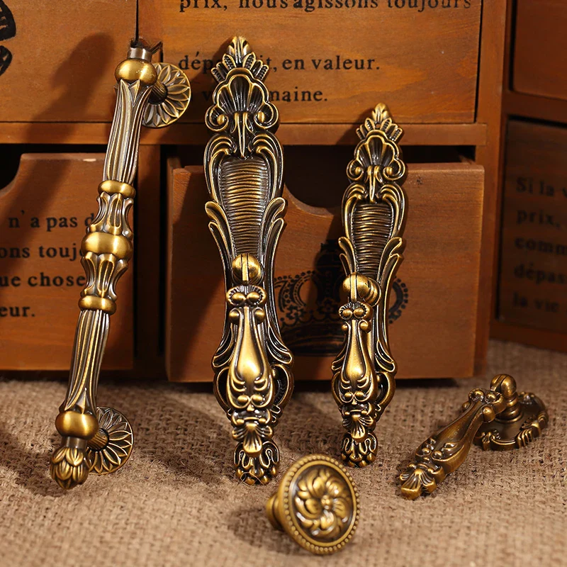 Decorative brass cabinet handles on a textured surface with a wooden background.