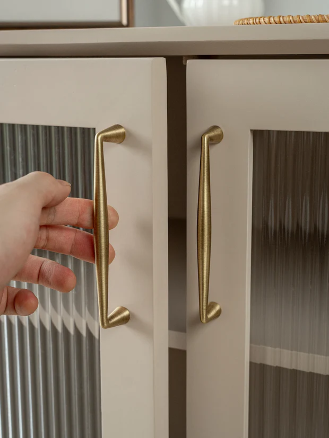 Hand opening a cabinet door with gold handles