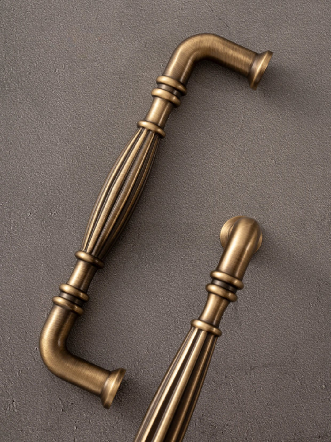 Two brass cabinet handles on a gray background