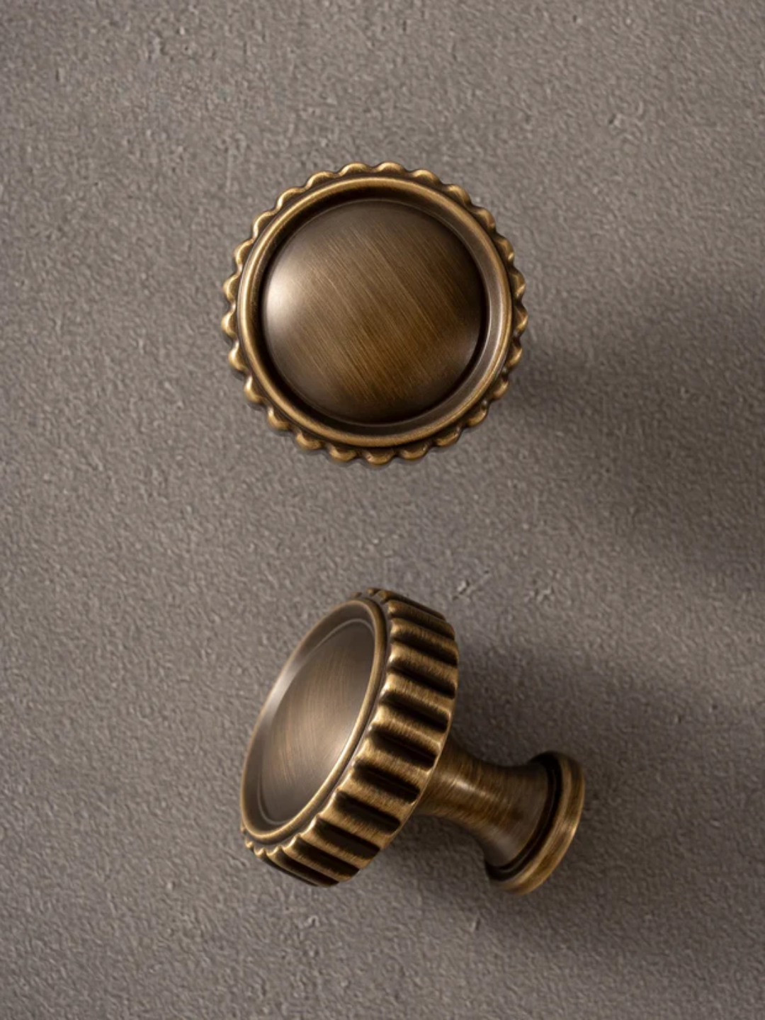 Two bronze cabinet knobs on a gray background