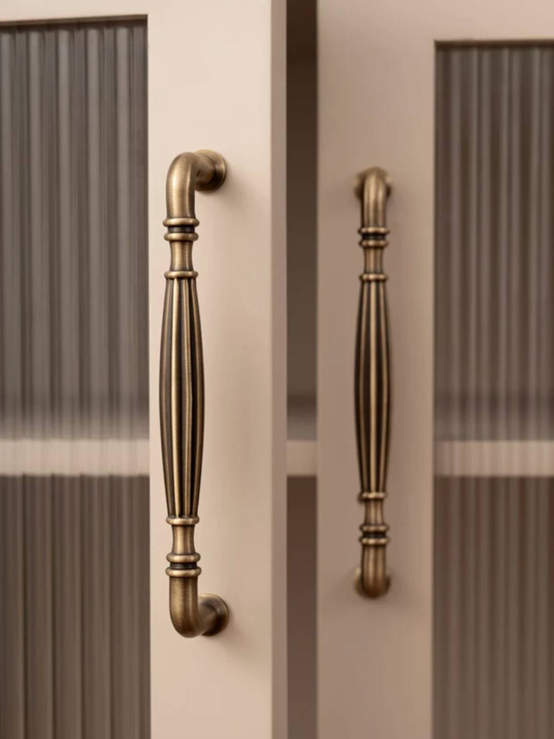 Close-up of ornate bronze cabinet handles on a neutral background