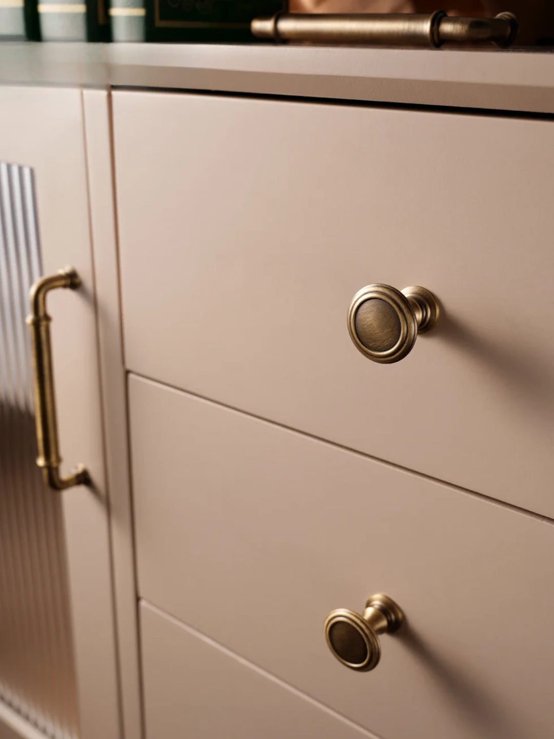 Close-up of a kitchen cabinet with gold handles on a neutral background