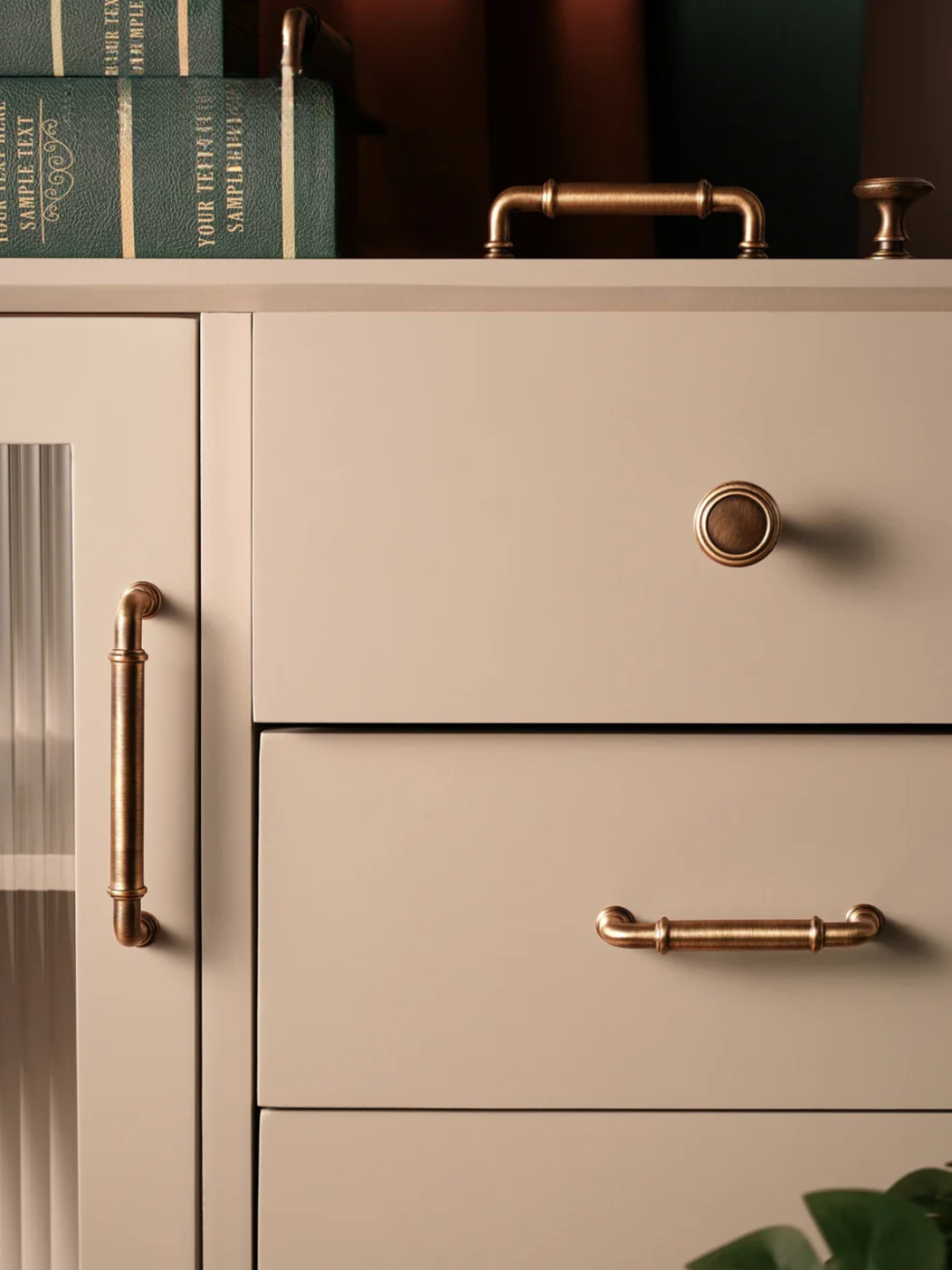 Beige cabinet with brass handles and books in the background