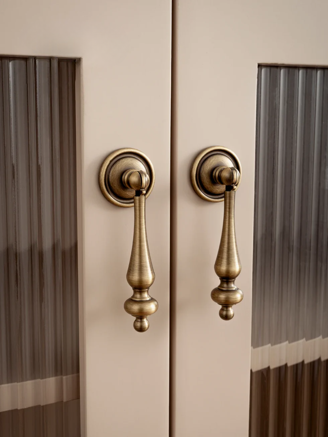 Close-up of a door with ornate brass handles and glass panels.