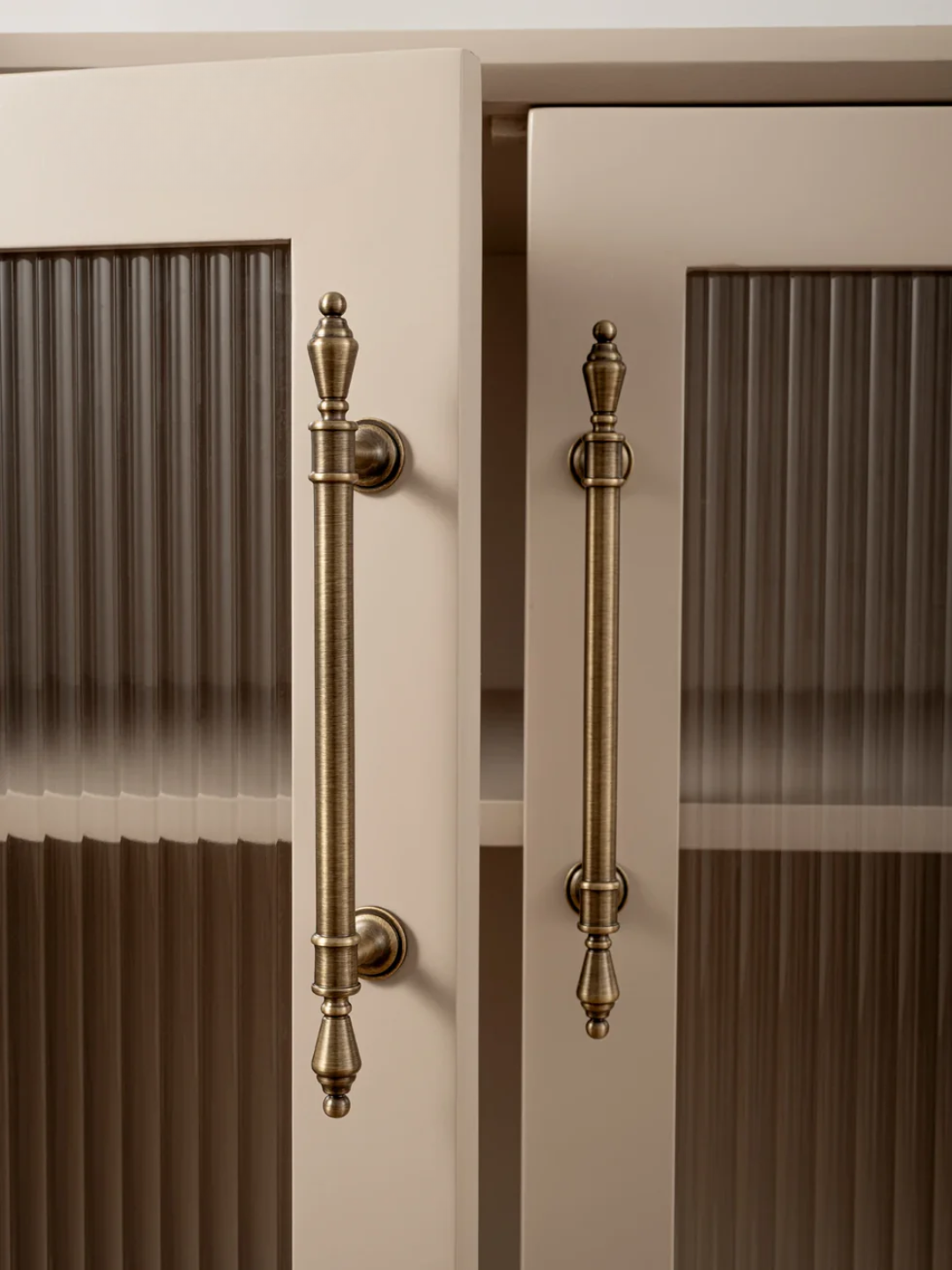 Close-up of a cabinet with decorative brass handles on a neutral background