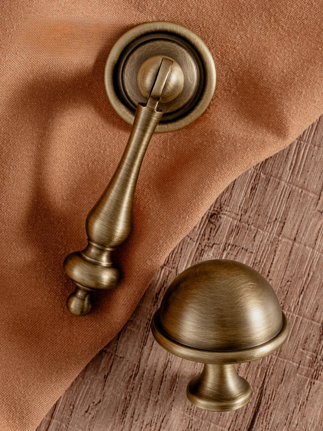 Bronze door handle and knob on a wooden surface with brown fabric background