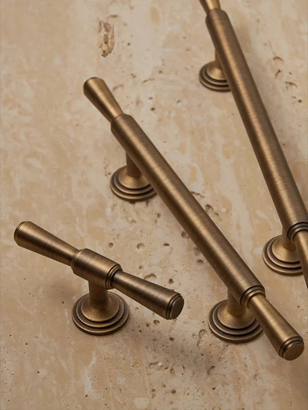 Brass cabinet handles on a beige stone background with 'Santaya' branding.