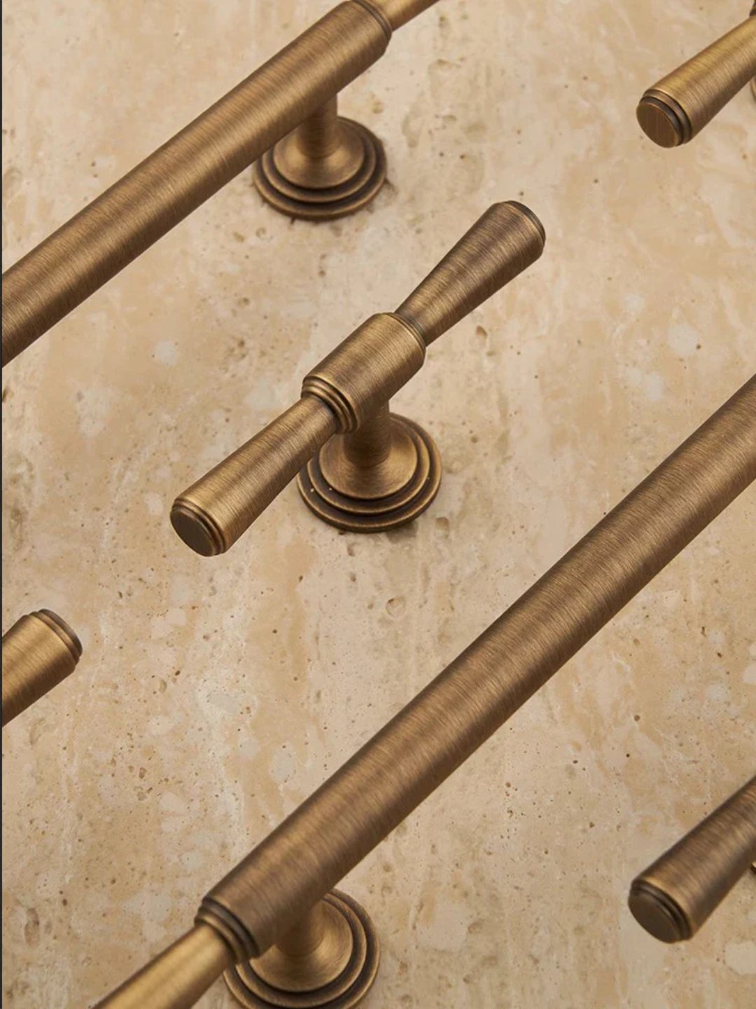 Close-up of bronze cabinet handles on a beige surface