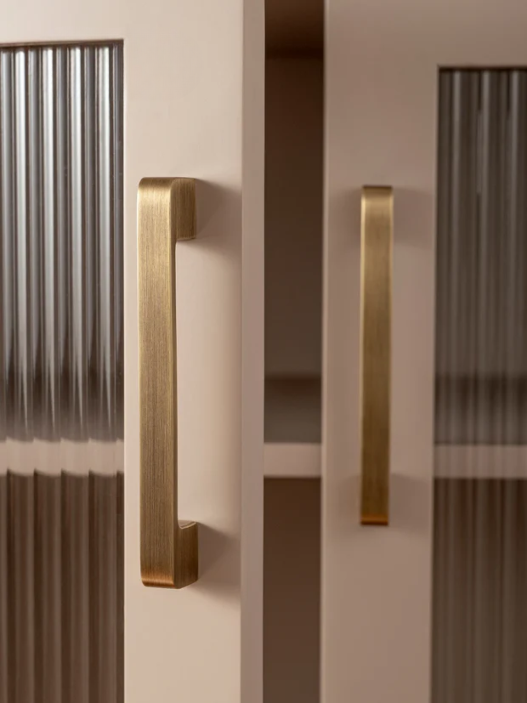 Close-up of two gold handles on a door with a neutral background