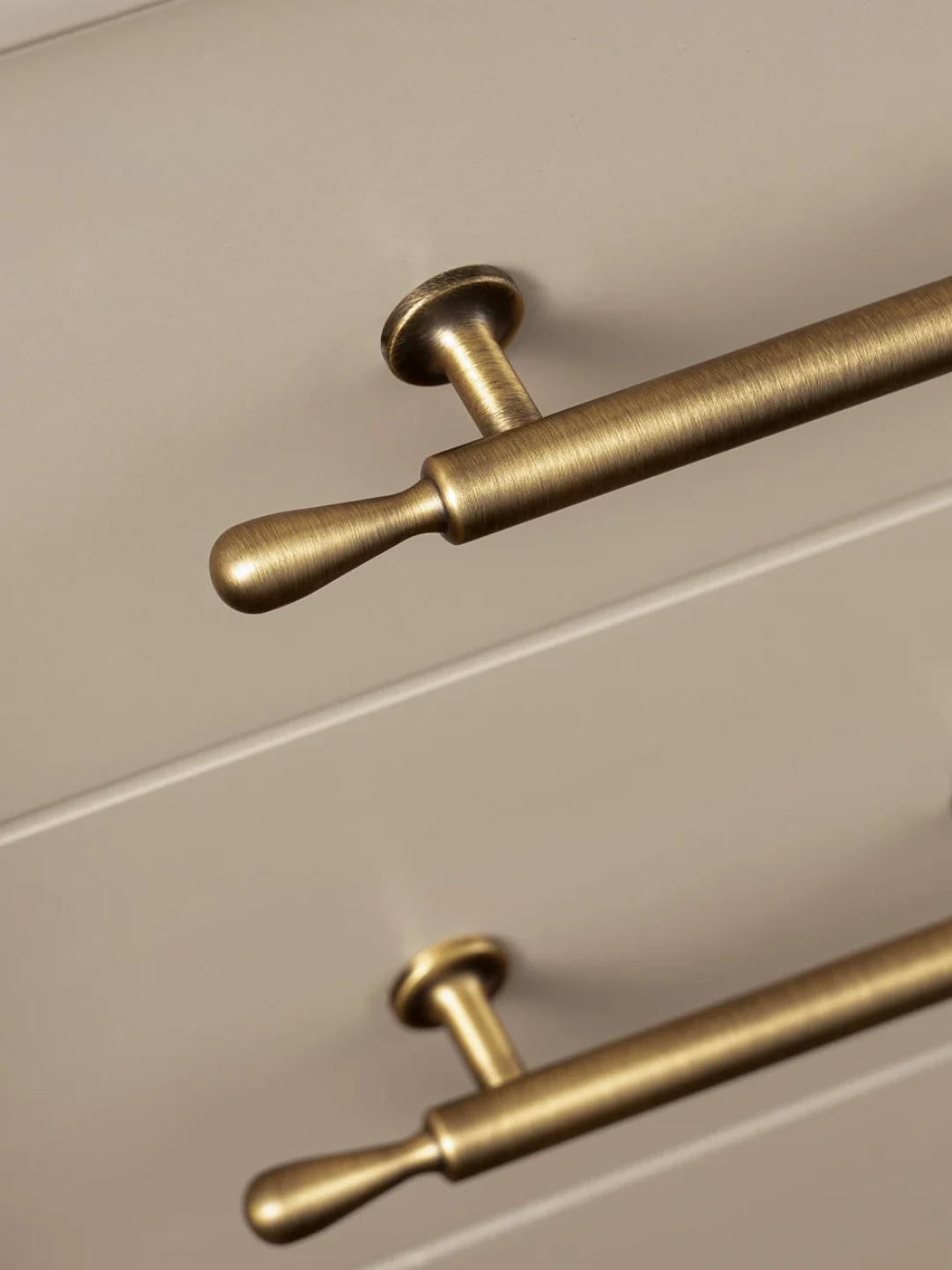 Close-up of gold cabinet handles on a beige drawer