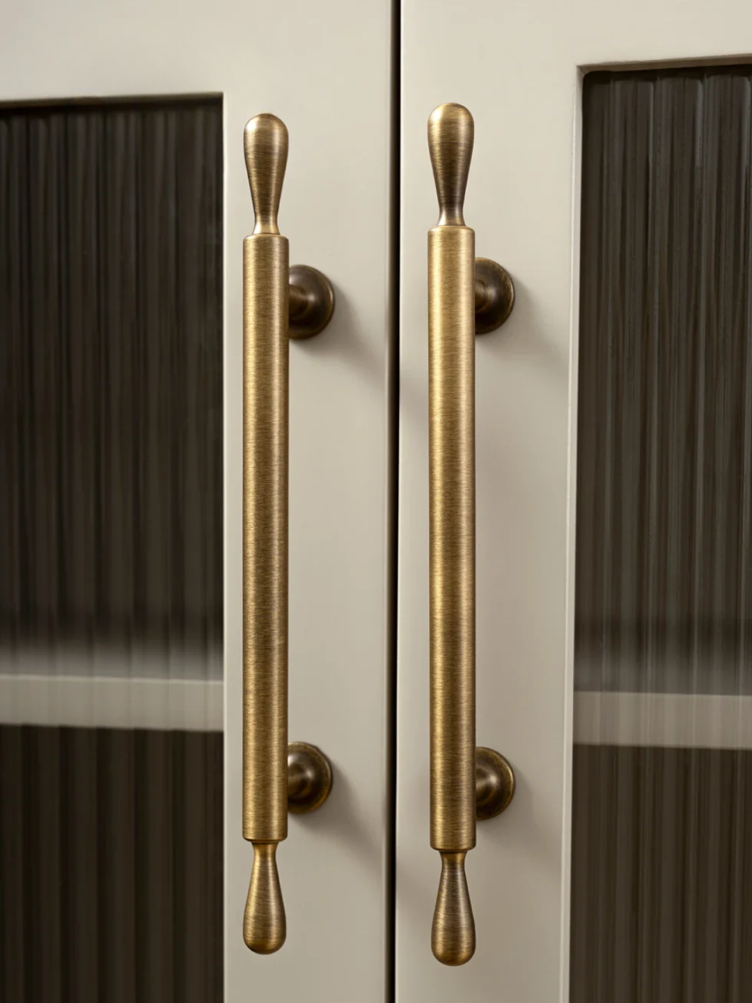 Brass door handles on a glass door with 'Santaya' branding.