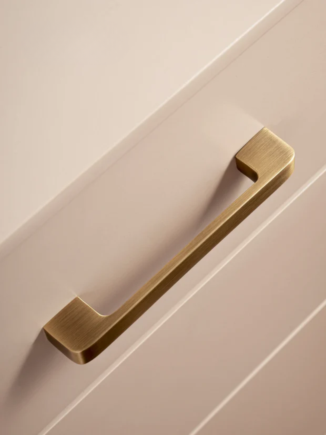 Brass cabinet handle on a beige cabinet door