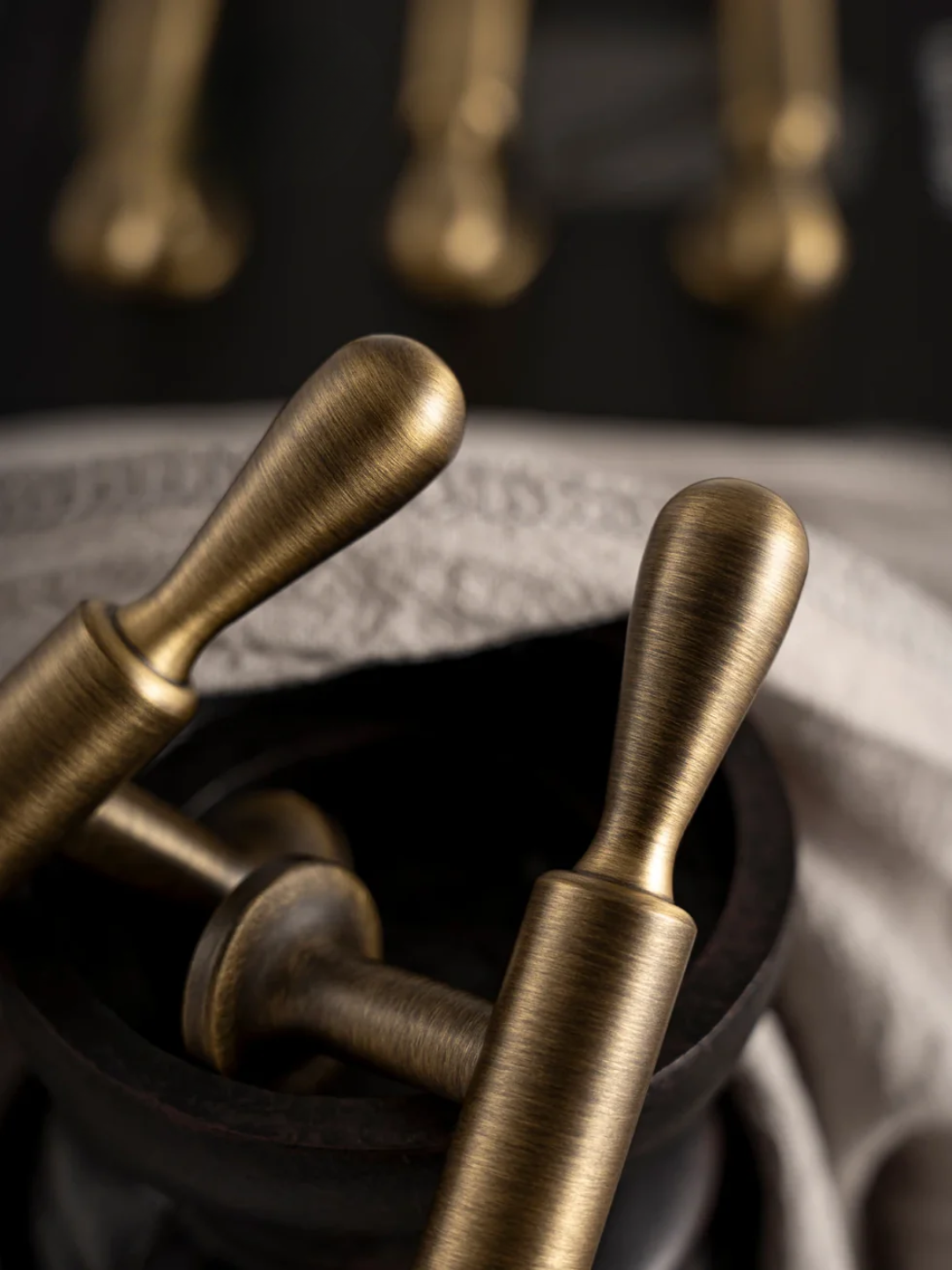 Bronze-colored tools or instruments in a black container on a textured surface.