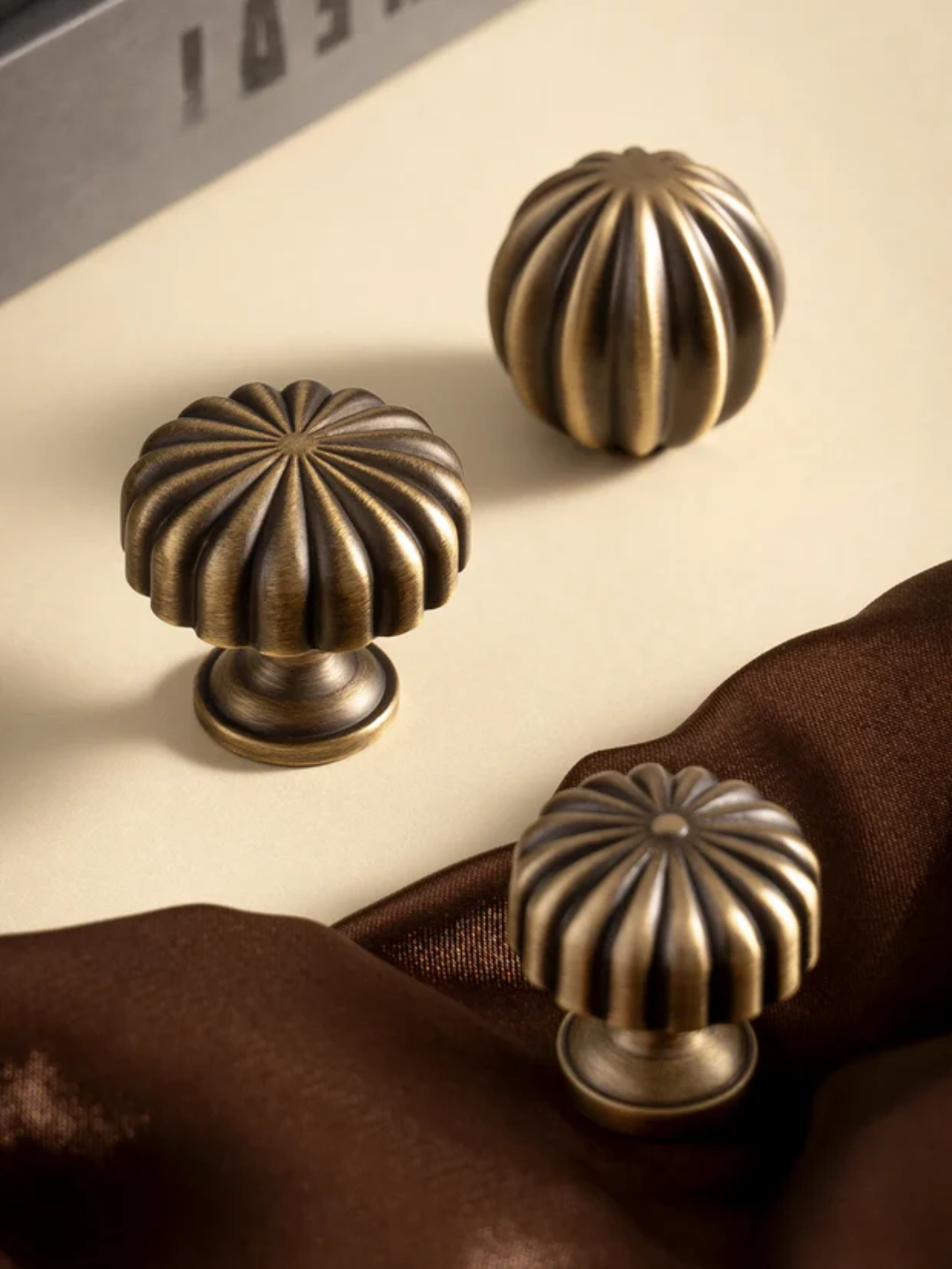 Three bronze cabinet knobs on a textured surface with 'Santaya' branding.