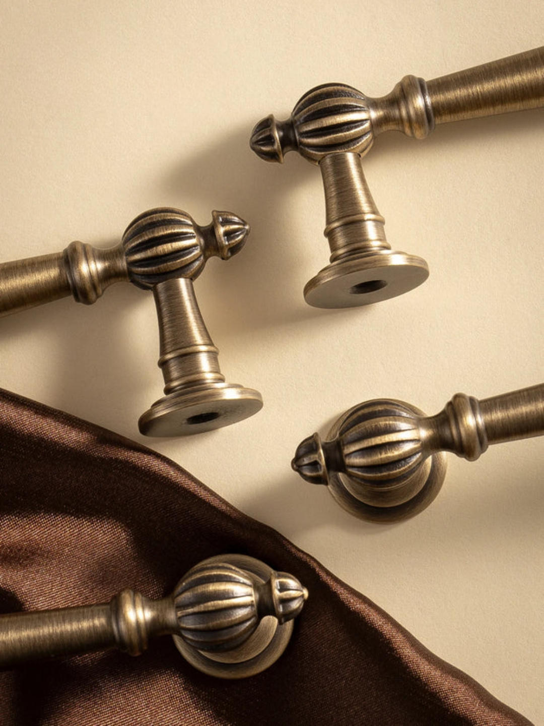 Bronze curtain rods with decorative ends on a beige background