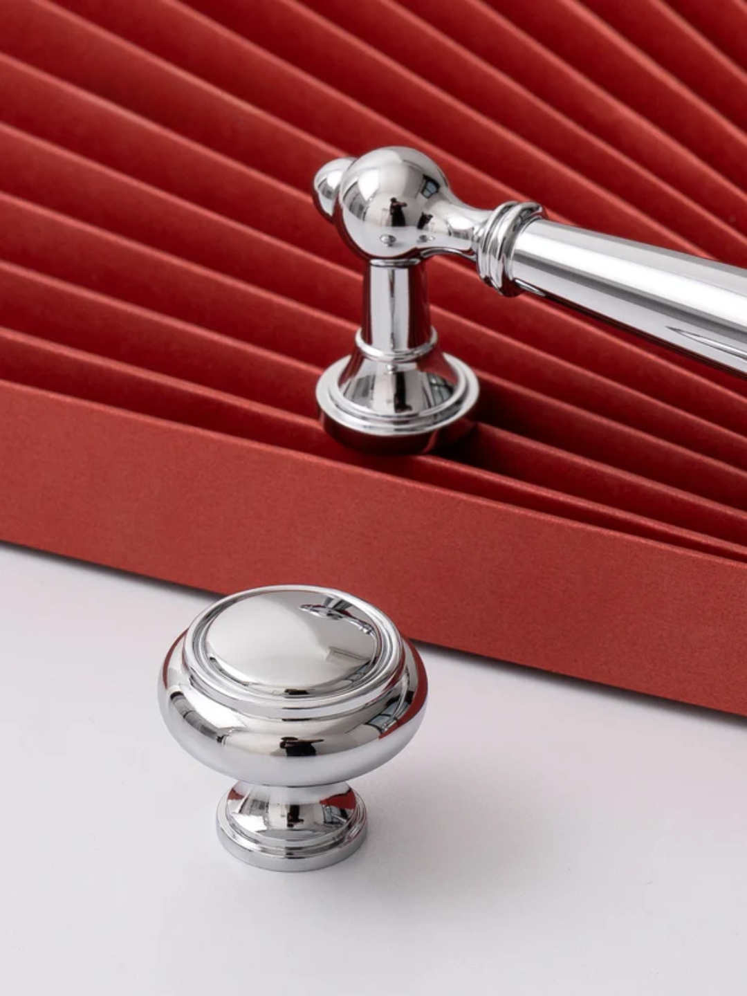 Chrome cabinet handle and knob on a red and white background