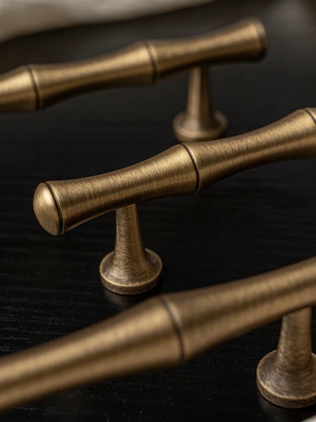 Close-up of bronze cabinet handles on a dark surface