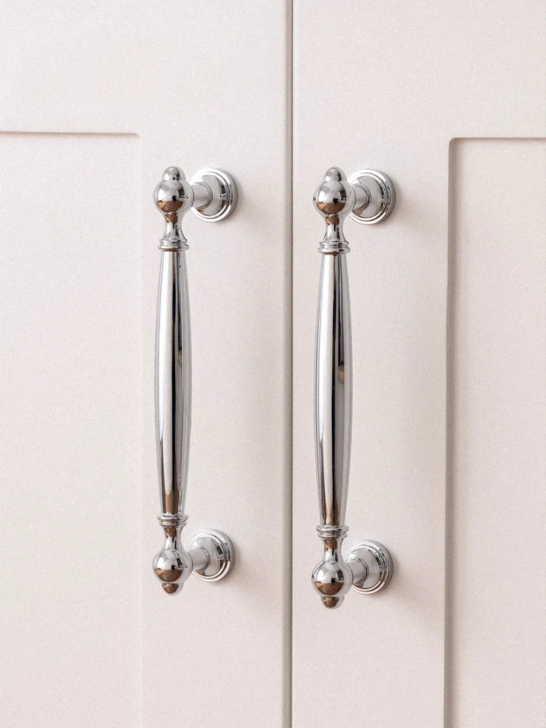Close-up of metallic cabinet handles on a light-colored cabinet door with 'Santaya' branding.