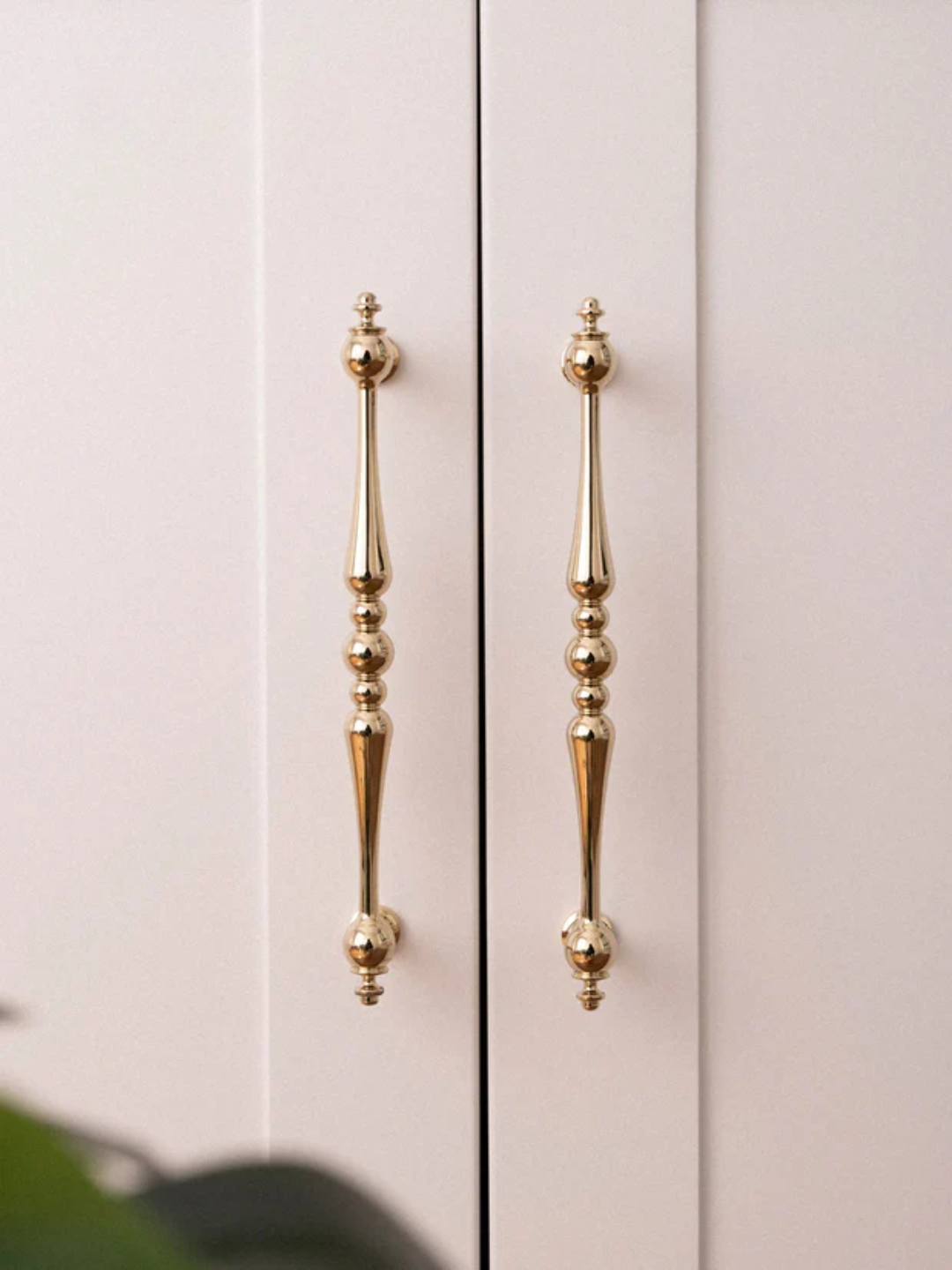 Close-up of a cabinet with gold handles on a light background.