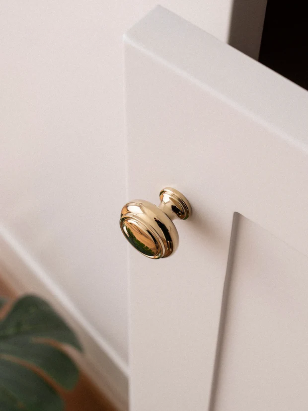 Gold cabinet knob on a white cabinet door