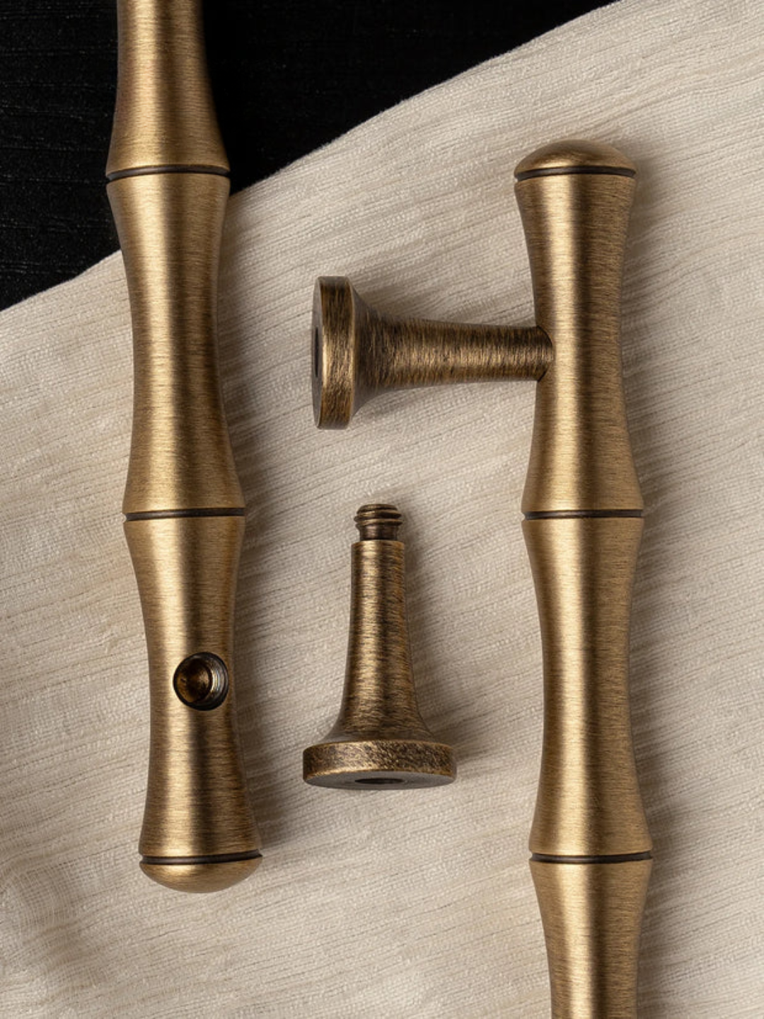 Three brass curtain rods of different lengths on a textured surface