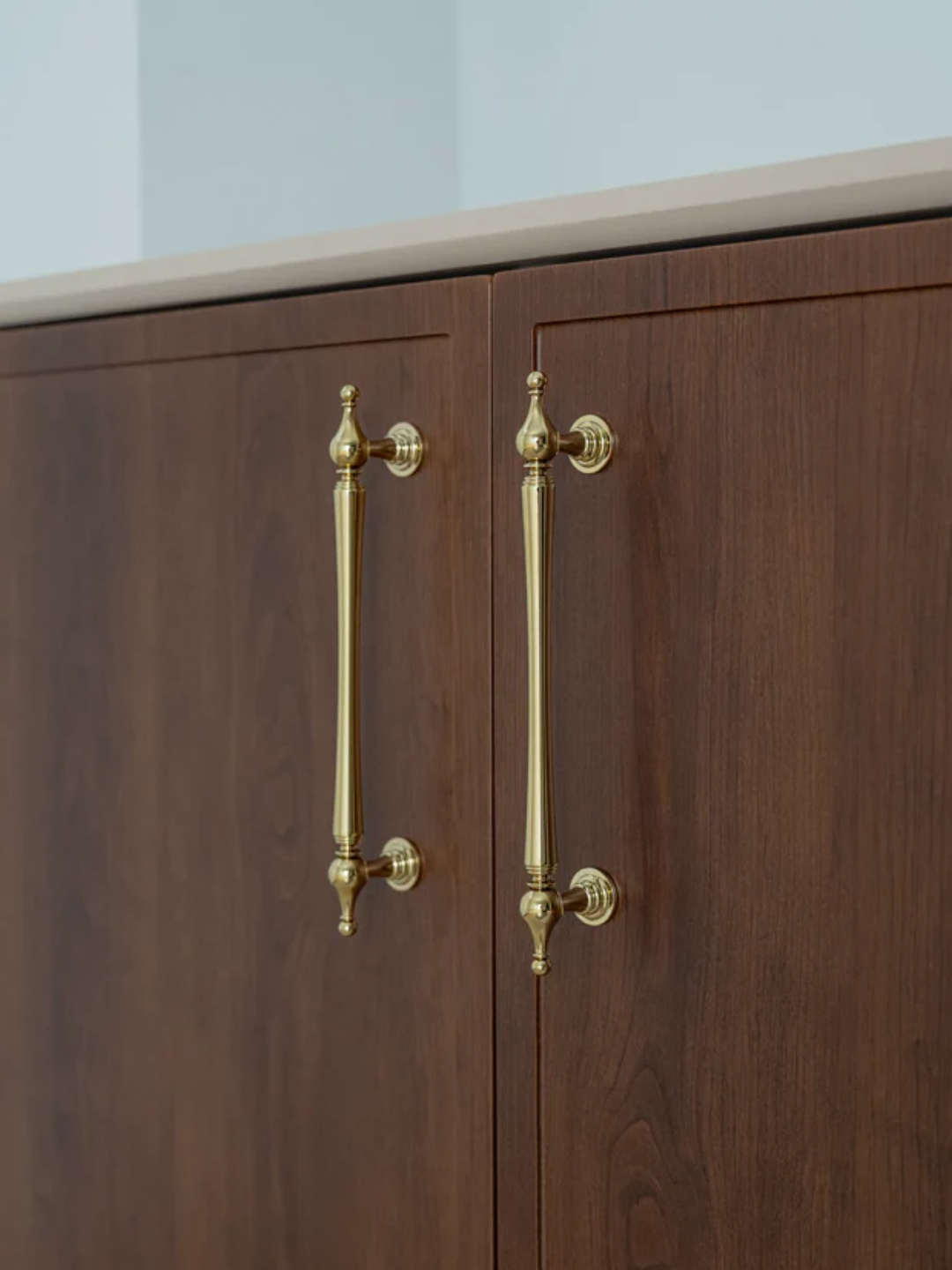 Wooden cabinet with brass handles on a light background